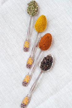 Assortment of powder spices on spoons on a light background