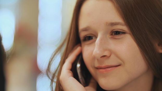 Cute young girl talking on a cell phone. Close-up.