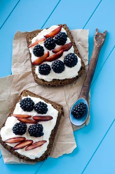 Sandwiches with sweet cheese and berries in blue wooden background