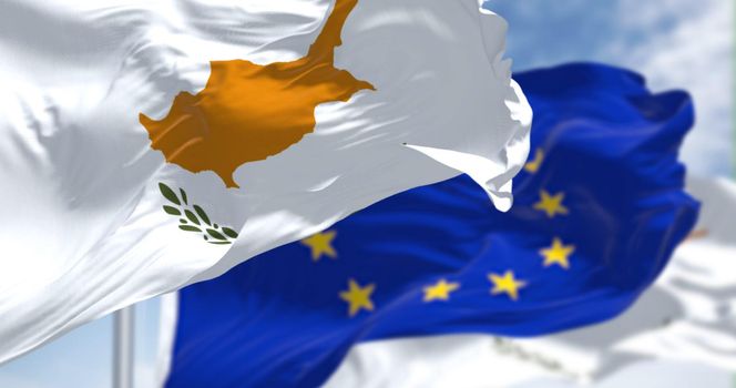 Detail of the national flag of Cyprus waving in the wind with blurred european union flag in the background on a clear day