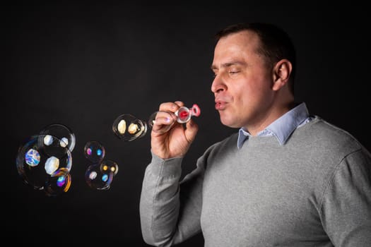handsome man in a suit is blowing soap bubbles.