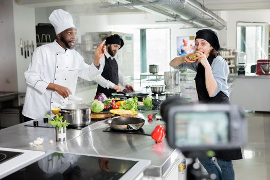 Gastronomy experts in restaurant professional kitchen cooking gourmet dish while recording culinary course.