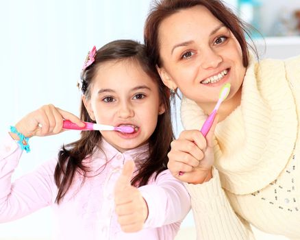 Mother and daughter brush their teeth.