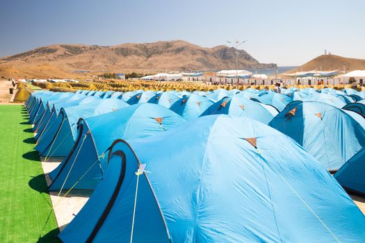 camping with a large number of tourist tents in an improvised festival town on the coast of the warm sea