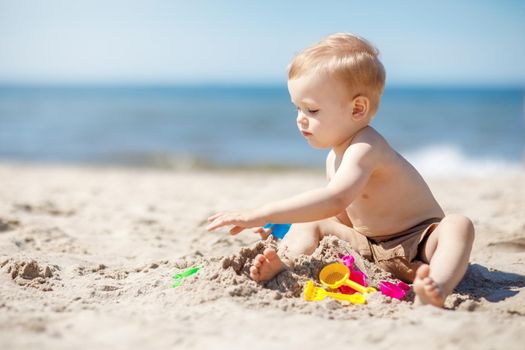 Baby boy play on beach, sand near sea
