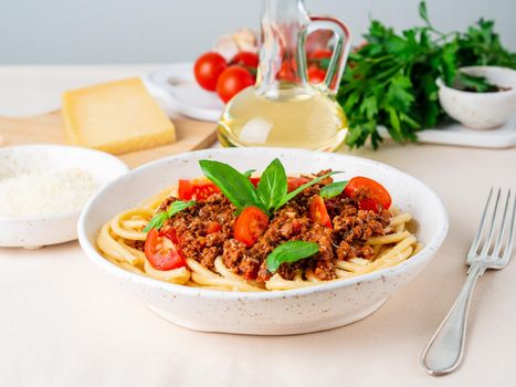 pasta bolognese with tomato sauce, ground minced beef, basil leaves on background