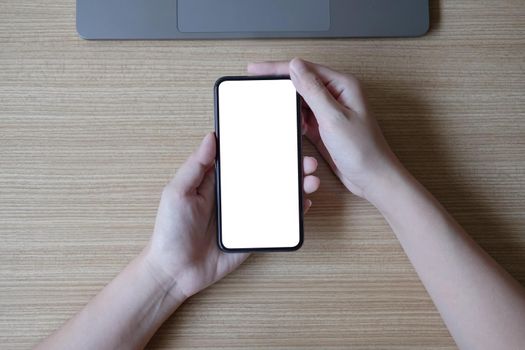 Woman hand holding smartphone with blank white screen on workplace