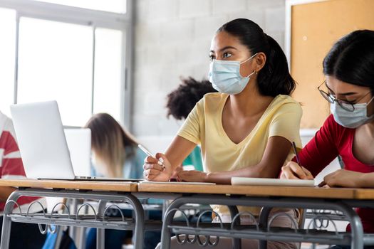 Teen latina girl student wears protective face mask in high school class. Copy space.