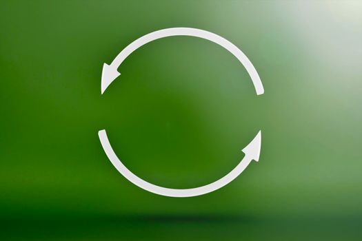 Ecology, recycling symbol, white arrows form a circle. 3D image on a green background. Green products, green renewable energy, graph pointing up and down