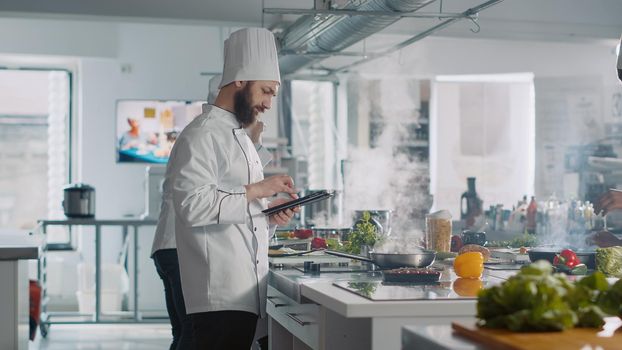 Male cook analyzing culinary recipe on digital tablet in kitchen