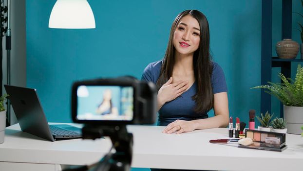 Content creator recording beauty videoblog with phone camera, doing makeup tutorial to give tips. Lifestyle blogger filming video on camera with streaming equipment and cosmetics.