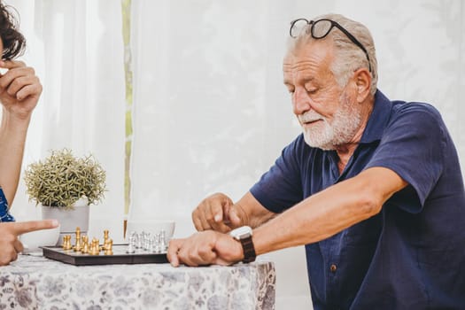 Old man playing Chess board game at home for training brain memory and thinking.