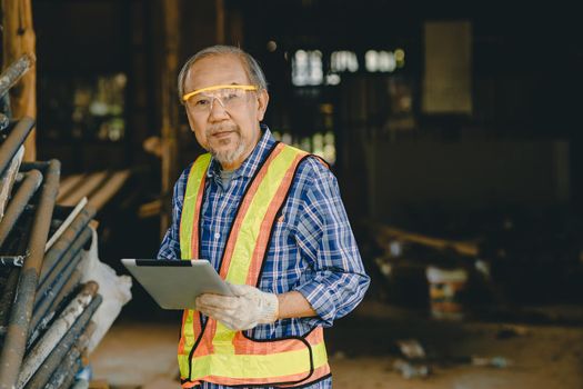 Portrait Smart elder engineer worker foreman using tablet computer technology at construction site.