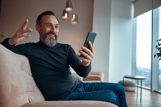 Happy bearded man sitting, resting and talking on mobile phone
