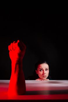 woman afraid of red hand, symbol of dictatorship, black background
