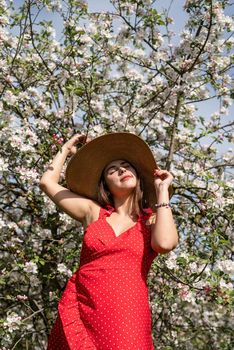 Young caucasian woman enjoying the flowering of an apple trees