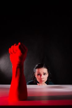 woman afraid of red hand, symbol of dictatorship, black background