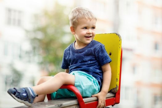Happy boy sits on playground swing chair
