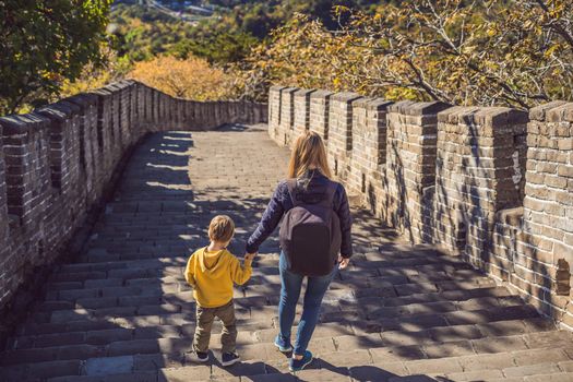 Happy cheerful joyful tourists mom and son at Great Wall of China having fun on travel smiling laughing and dancing during vacation trip in Asia. Chinese destination. Travel with children in China concept