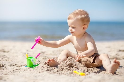 Little child making sand castles at the beach