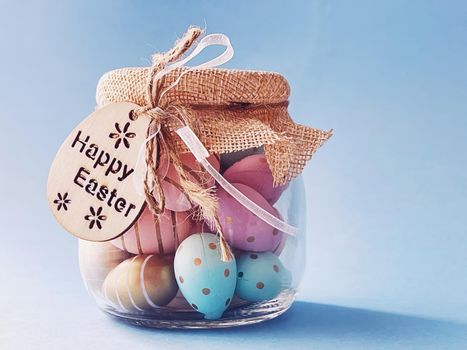 Happy Easter. Colourful painted easter eggs in glass jar on blue background, Christian religion and holiday