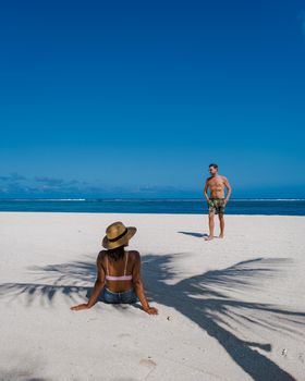 Le Morne beach Mauritius,Tropical beach with palm trees and white sand blue ocean couple men and woman walking at the beach during vacation
