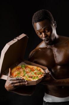 Fit surprised black man with pizza in cardboard box. Undressed handsome african man with pizza delivered to costumer