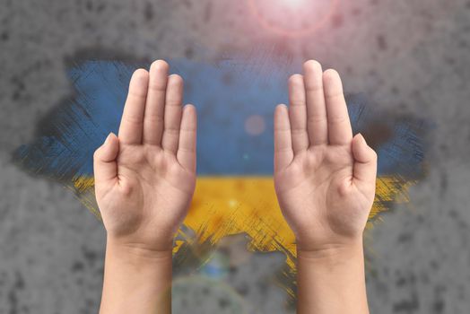 Support for Ukraine and solidarity. Children's hands on the background of the Ukrainian flag. The concept of confrontation and struggle