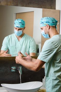 Surgeon is looking at the cleanliness of his hands after washing under a stream of water. Hygiene before working with patients