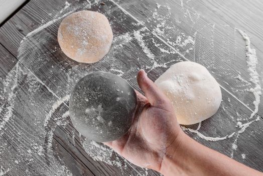 Wheat dough ball with flour in hands. Cooking pizza with italian white dough. Food blanks in restaurant