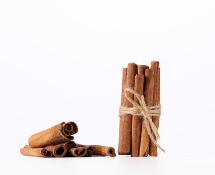 dry cinnamon sticks tied with a rope on a white background