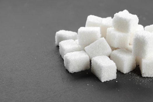 White sugar cubes over black background close up