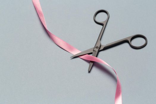 Grand Opening illustrated with scissors and a pink ribbon on a gray background