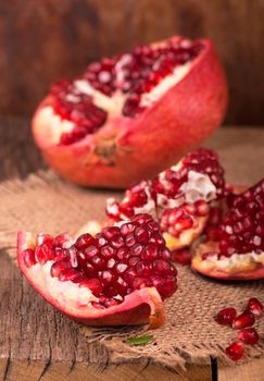 Juicy pomegranate and its half Beautiful composition with juicy pomegranates, on old wooden table