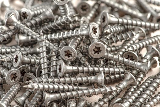 Close-up of universal silver screws with torx head. Self-tapping screws for wood, plywood or chipboard. Torx screws close up.