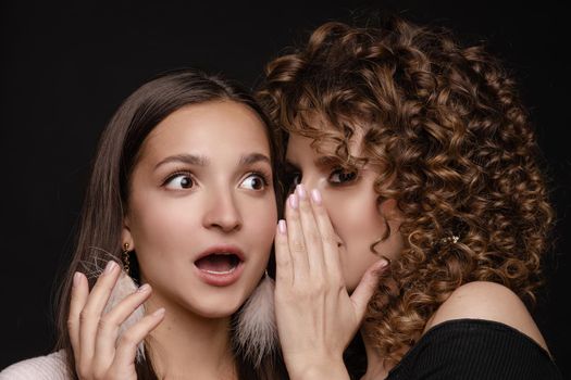 Shocked brunette posing while friend whispering secret