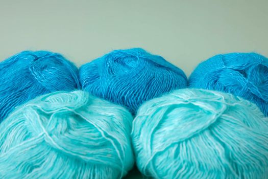Five fluffy skeins of blue and turquoise yarn selective focus knitting aesthetics