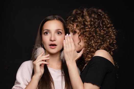 Shocked brunette posing while friend whispering secret