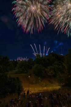 Colorful fireworks with people looking and the Munich Olympic Tower in the background, Munich, Germany