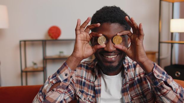 Man freelancer holding two gold coins BTC at home, successful developer programmer stock trader