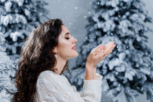 New year celebration. Attractive girl close-up with falling snow . Young woman weared in a warm white pullover and white socks.