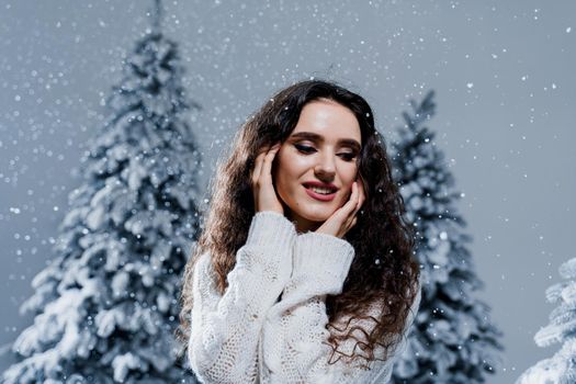 New year celebration.Happy girl with falling snow. Young woman weared in a warm white pullover and white socks. Winter holidays in snowy day.