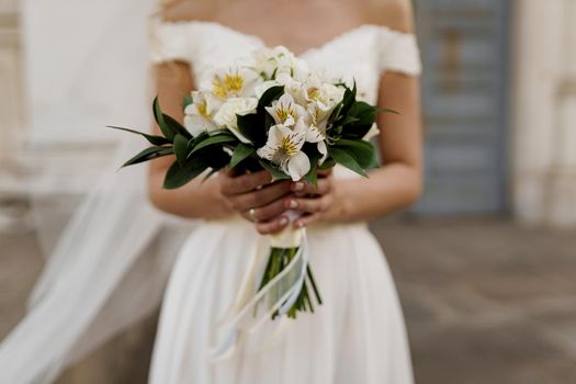 Wedding bouquet with white roses and green leaves. Bride in dress holds bouquet. Advert for wedding agency