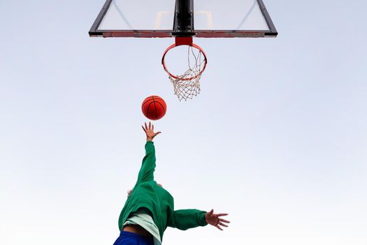 woman shooting in basketball hoop seen from below