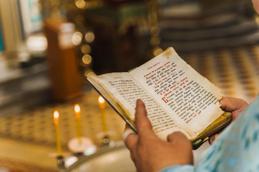 Holy book opened in priest hands in church. Priest reads pray. Orthodox faith. Equipment for praying. Pray for people life. Pray to god.