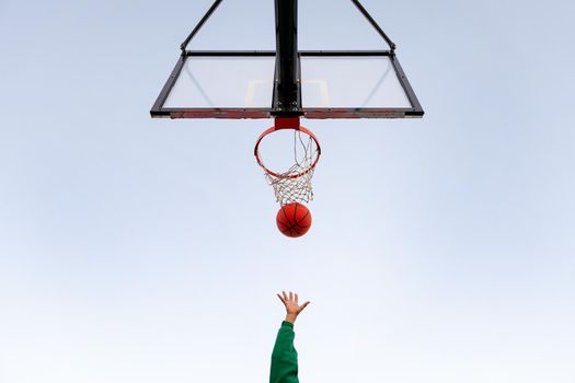 hand shooting in a basketball hoop seen from below