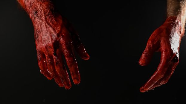 Male bloody hands on a black background.