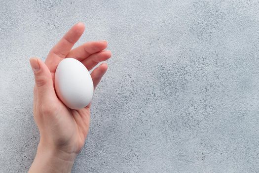 Human hand holding a white egg