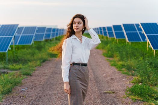 Girl stand between 2 Solar panels row on the ground at sunset. Free electricity for home. Sustainability of planet.