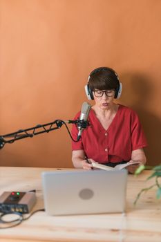 Middle-aged female radio presenter talking into the microphone and reading news - radio broadcast online concept